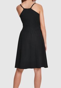 Svart ärmlös klänning med en sittande överdel och utsvängd kjol. Har justerbara axelband och en slät, mjuk textur. Enkel design.