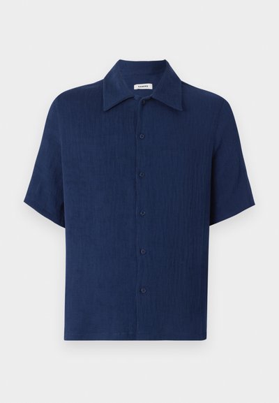 Camicia a maniche corte blu navy realizzata in un tessuto testurizzato, con un collo classico e una chiusura con bottoni frontale con bottoni distanziati uniformemente.