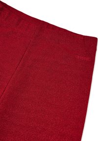 Rødt elastisk stoffpanel med teksturert overflate og subtil glans. Inkluderer en preget logo øverst til høyre.