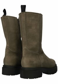 Botas de tobillo de ante topo con una suela de goma negra gruesa, cierre lateral con cremallera y una lengüeta en la parte superior. Los detalles cosidos acentúan el diseño.