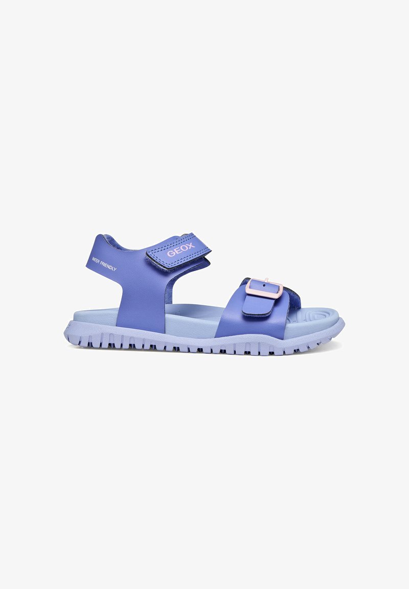 Sandale bleue pour enfants avec brides ajustables, semelle rembourrée, grip texturé, étiquetée « Water Friendly » et marquée « GEOX » sur la bride de cheville.