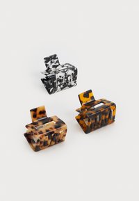 Three hair clips: one black and white marbled, two tortoiseshell in brown and black hues, all made of glossy plastic with a textured finish.