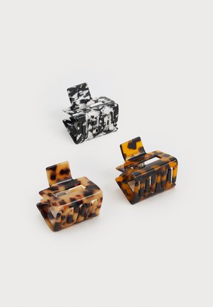 Três ganchos de cabelo: um em mármore preto e branco, dois em padrão tartaruga nas tonalidades castanha e preta, todos feitos de plástico brilhante com um acabamento texturizado.