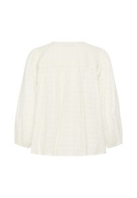 Blouse blanche à manches longues et coupe ample, vue de dos, avec une texture verticale discrète et un ourlet droit. Aucun système de fermeture visible.