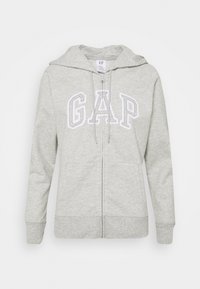 Felpa grigia con zip realizzata in morbido tessuto misto cotone. Presenta un cappuccio con coulisse, tasche frontali e il logo "GAP" in testo bianco sul petto.