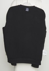 Svart sweatshirt med ribbade ärmslut och nederkant, rundhalsad design. Tyget verkar ha en texturerad yta, med en etikett synlig vid bakhalsen.