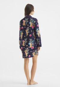 Camicia da notte blu navy stampata con tigri, piante e cuori. Maniche lunghe con polsini a bottone e fessure laterali. Realizzata in tessuto morbido.