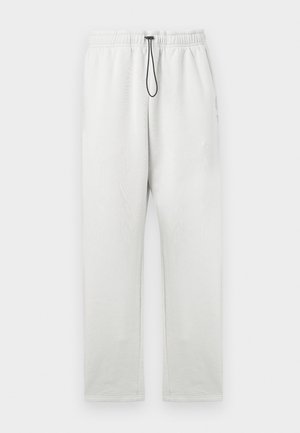 Pantalon de survêtement gris clair en tissu doux, doté d'une taille élastique avec un cordon de serrage noir et d'une coupe droite. Sans poches.
