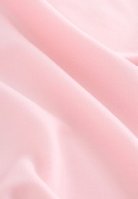 Zachte roze stof met zachte plooien en een gladde textuur, met fijne geribbelde patronen op het oppervlak.