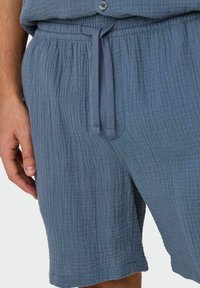 Lichtblauwe textuurshorts met een trekkoord in de taille, voorzien van een subtiele gekreukte patroon en zijzakken voor functionaliteit.