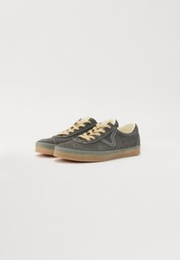 Mörkgrå mockaskor med beigefärgade snören, rund tå, låg profil och en lätt gummisula. Sido-sömmar framhäver designen.