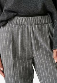 Graue gestreifte Hose mit elastischem Bund, zeichnet sich durch eine weiche Textur und hellgraue vertikale Streifen auf einem dunkleren grauen Hintergrund aus.