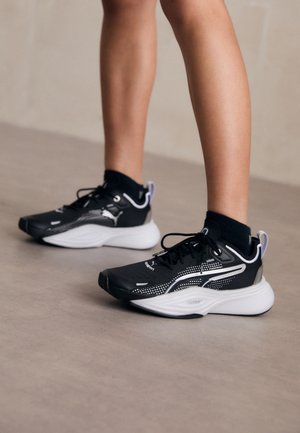 Svarta sportskor med vita detaljer, mesh-ovandel, snörning och dämpad häl. Har en texturerad sula för bra grepp.