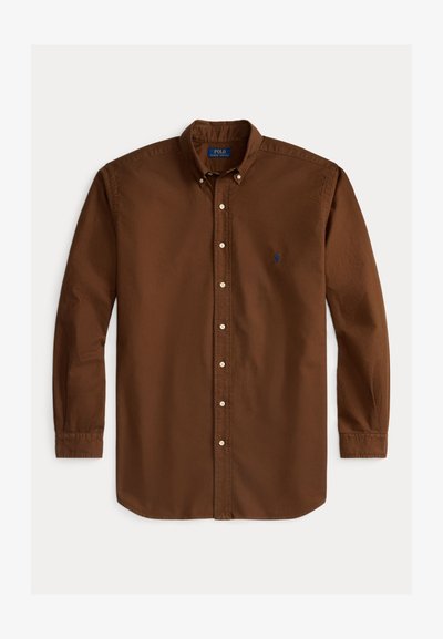 Camisa de botão de mangas longas castanha, feita de algodão, com um colarinho clássico, botões brancos e um pequeno logótipo azul no lado esquerdo do peito.