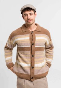 Brun och krämrandig cardigan i fluffigt material, med krage, knappstängning och stickade manschetter med horisontella ränder.