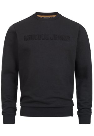 Sudadera negra con un logo texturizado de "INDICODE JEANS", cuello redondo y puños acanalados. Incluye un detalle con cremallera en el costado.