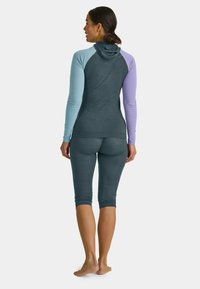 Hooded athletic top in dark gray, with light blue and lavender sleeves. Paired with dark gray capri leggings, smooth texture, fitted design.