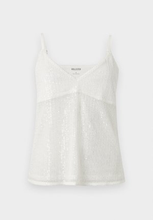 Λευκό αμάνικο τοπ με V-λαιμόκοψη και παγιέτες, λεπτές ρυθμιζόμενες τιράντες, ελαφρύ ύφασμα και διακριτικές λάμψεις.