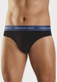 Sorte bomullstruser med blå midjebånd som har "COPENHAGEN STUDIOS" i hvit skrift. Glatt tekstur, tettsittende design og minimal dekning.