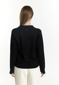 Black knit sweater with long sleeves, ribbed collar and cuffs, and a fitted bottom hem. Simple design, no visible patterns or hardware.