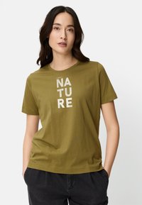 Olive green cotton t-shirt with short sleeves, featuring the word "NATURE" printed vertically in light-colored text. Simple round neckline.