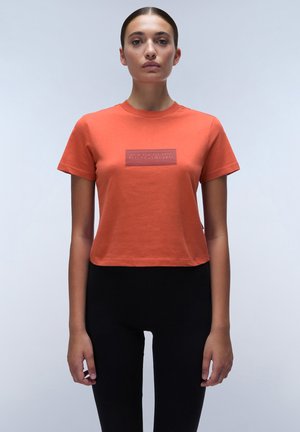 Korte mouwen, cropped T-shirt van oranje katoen met een rechthoekig tonale logopatch op de borst. Gemaakt in combinatie met hoge zwarte leggings.