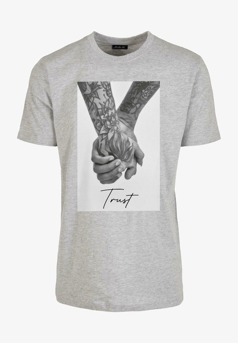 Szary bawełniany t-shirt z nadrukowanym czarno-białym zdjęciem rąk z misternymi tatuażami oraz słowem „Zaufaj” zapisanym kursywą.