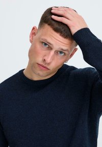 Dunkelblauer Pullover mit Rundhalsausschnitt, aus einem weichen Strickstoff gefertigt. Verfügt über lange Ärmel und eine strukturierte Oberfläche. Keine Muster oder Verzierungen.