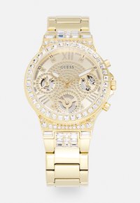 Montre Guess dorée avec un cadran texturé, un bezel orn�é de cristaux scintillants et des sous-cadrans chronographes. Bracelet en maillons métalliques avec une finition brillante.