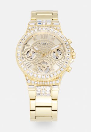 Relógio Guess em tom dourado com um bezel de cristais brilhantes, mostrador texturizado e submostradores de cronógrafo. Bracelete em metal com acabamento brilhante.