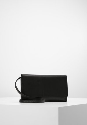 Zwarte rechthoekige leren clutch met een dunne band, geplaatst op een wit voetstuk tegen een effen witte achtergrond.