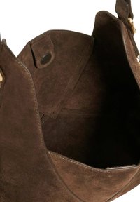 Brown suede handbag interior with a smooth texture, featuring a magnetic closure and clean, stitched edges.