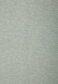 Šviesiai žalia medžiaga su minkštu, šiek tiek tekstūruotu paviršiumi. Medžiaga atrodo vienoda, su subtiliu, tolygiu mezgimo raštu visame paviršiuje.