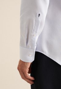 Witte shirt met een blauw micro-check patroon, knoopmanchetten en zwarte bloemenborduursels op de mouwen. Glad stoffen en aansluitend ontwerp.