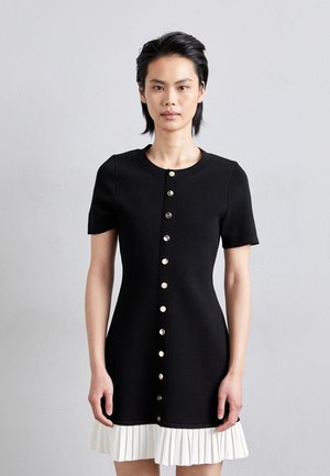 Rochie scurtă neagră cu mânecă scurtă, guler rotund, închidere cu nasturi aurii în față și tiv striat alb pentru contrast. Material neted cu un design ajustat.