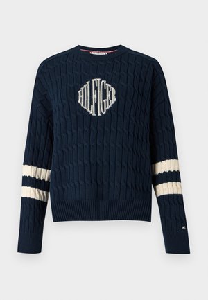 Granatowy sweter dzianinowy z kabelkowym wzorem, z białym haftowanym logo na klatce piersiowej i kremowymi paskami na rękawach.