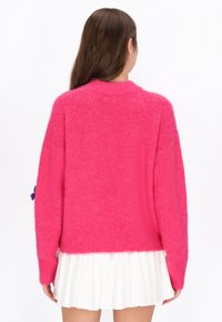 Heller pinker gestrickter Pullover mit lockerer Passform, langen Ärmeln und Rundhalsausschnitt. Verfügt über eine weiche Textur und Rippdetails am Saum.