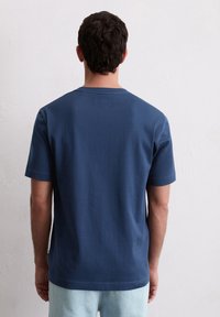 Marineblauwe katoenen T-shirt met korte mouwen, een ronde hals en een rechte zoom. Zichtbare stikseldetails op de zoom en mouwen.