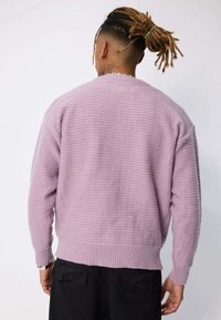 Pull léger violet avec un design texturé et côtelé. Doté d'un col rond et de manches larges. Présenté de dos, avec une coupe décontractée.