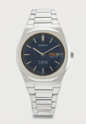 Ασημένιο μεταλλικό ρολόι χειρός με μπλε καντράν, εμφάνιση ημέρας και ημερομηνίας που δείχνει Σάββατο 9, και ασημένιους δείκτες ώρας και δείκτες.