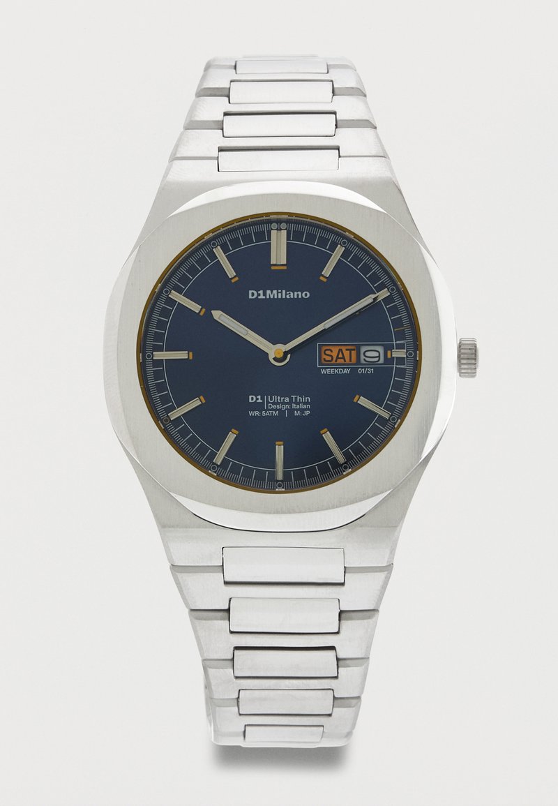 Ασημένιο μεταλλικό ρολόι χειρός με μπλε καντράν, εμφάνιση ημέρας και ημερομηνίας που δείχνει Σάββατο 9, και ασημένιους δείκτες ώρας και δείκτες.