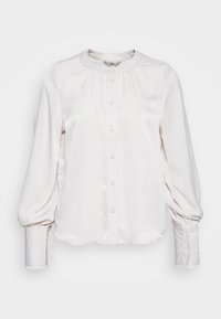 Blusa bianca in satin con maniche a sbuffo, morbida al tatto e colletto rotondo. Ha una chiusura frontale con bottoni abbinati.