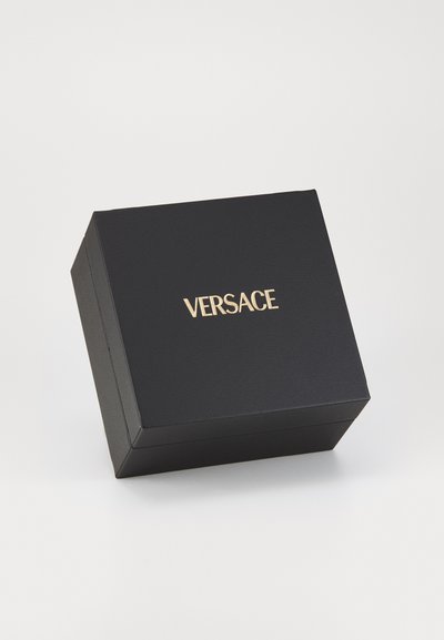 Boîte en carton noir avec une finition texturée, arborant un logo doré "VERSACE" à l'avant. Forme carrée avec un couvercle à charnière.
