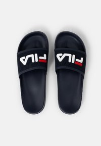 Navy blue slide sandals with a perforated strap. Features a white "FILA" logo with red accent. Made from smooth rubber material.