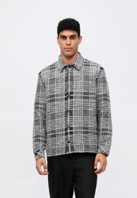 Πουκάμισο με κουμπιά σε γκρι και μαύρο καρό σχέδιο, με γιακά και μακριά μανίκια, φτιαγμένο από υφασματική υφή.