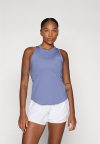 Fioletowy sportowy tank top wykonany z lekkiej tkaniny, z okrągłym dekoltem i bocznymi wcięciami, zestawiony z białymi szortami.