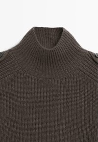 Maglione a collo alto in maglia marrone con texture a coste, bottoni sulle spalle e design spesso e chunky.