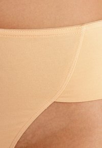 Beige rekbare stoffen ondergoed met ribbeltextuur, mid-rise ontwerp en een gladde afwerking langs de randen.