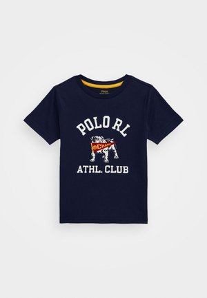 Camisa azul marino de manga corta con texto blanco "POLO RL ATHL. CLUB" y un bulldog sosteniendo un banderín rojo con la palabra "CHAMPS" en el frente.