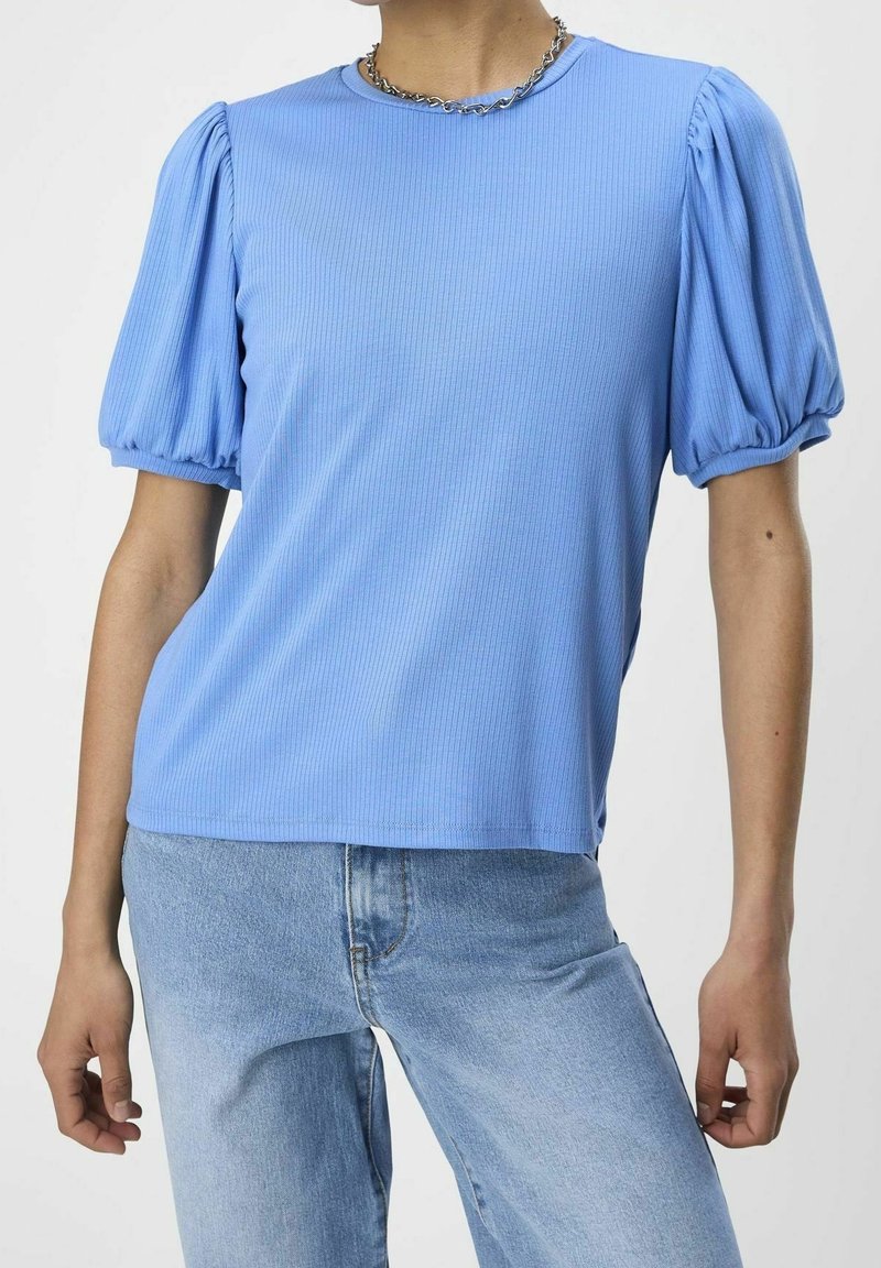 T-shirt bleu clair côtelé avec manches courtes bouffantes et encolure ronde, associé à un jean en denim bleu clair.